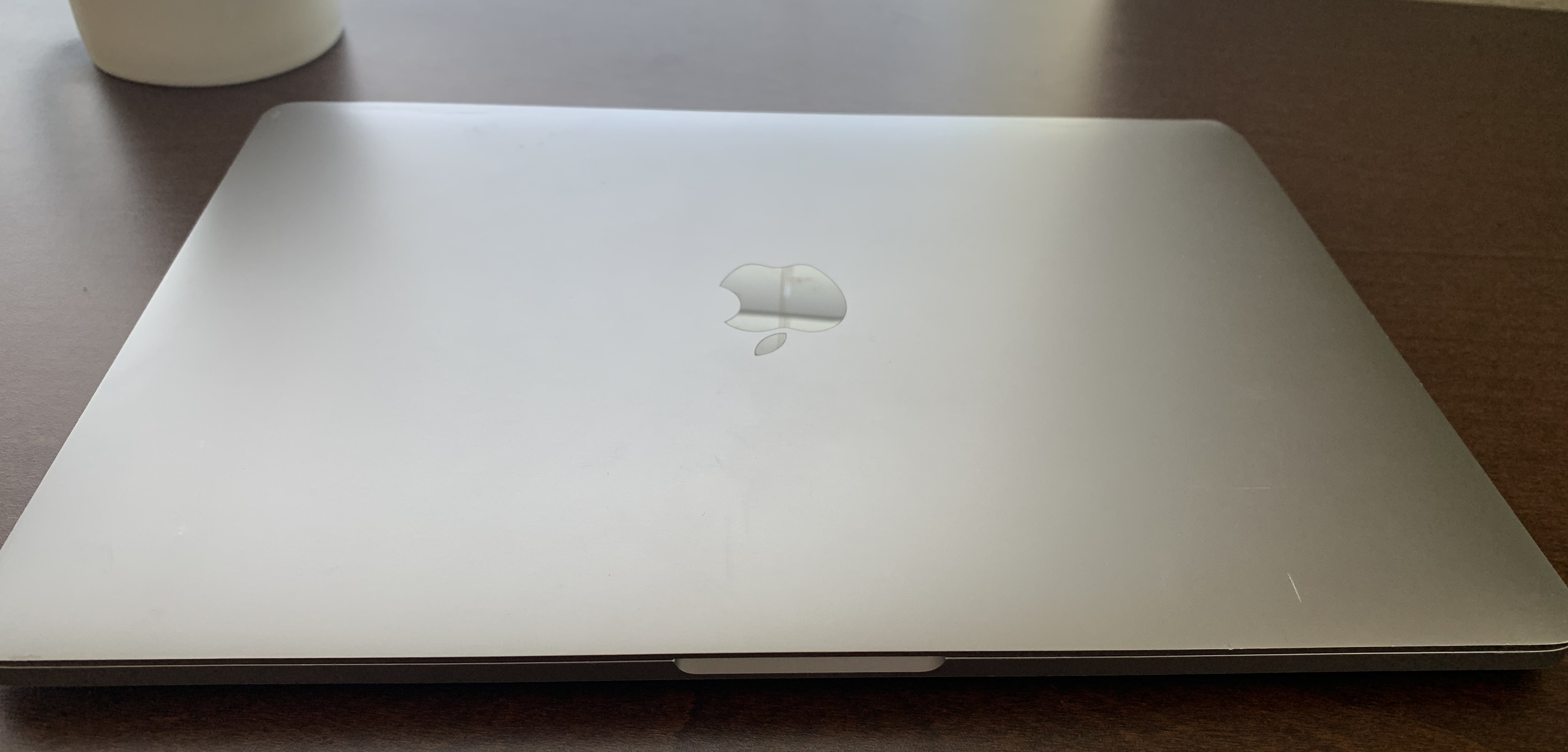 a space-gray macbook, closed shut. the metallic apple logo has a few scratches